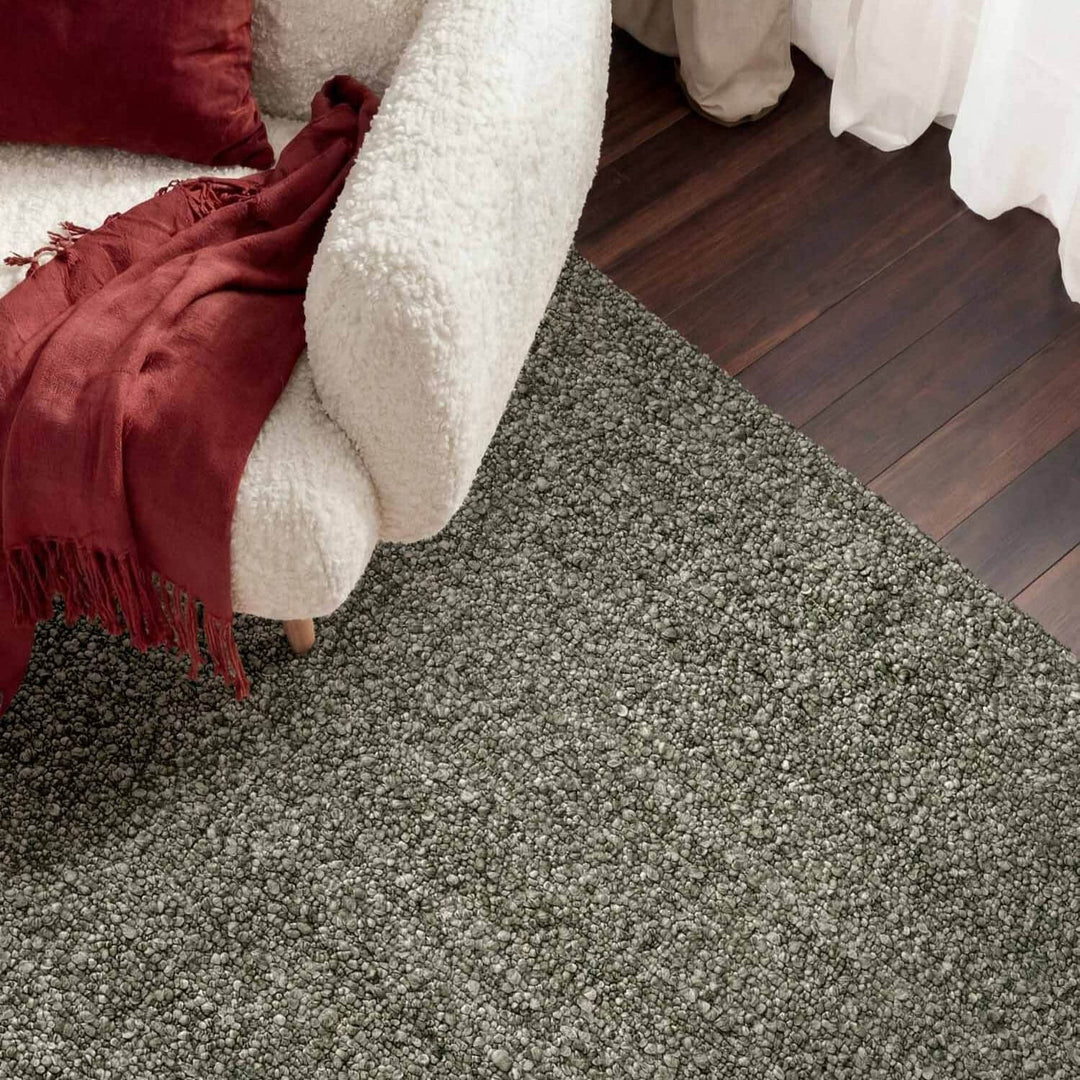 Gray carpeted floor with a white sofa and red blanket in the foreground