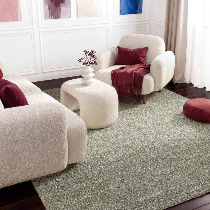 Living room with white armchairs, a green rug, and red accents.