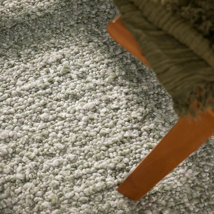 Close-up of a green carpet with a brown object partially visible