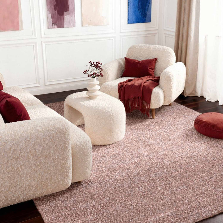 Living room with beige armchairs, a white ottoman, and red cushions.
