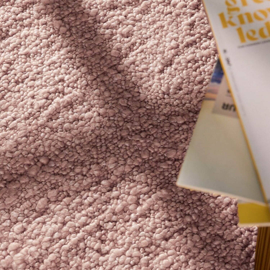 Close-up of a textured pink fabric with a product partially visible.