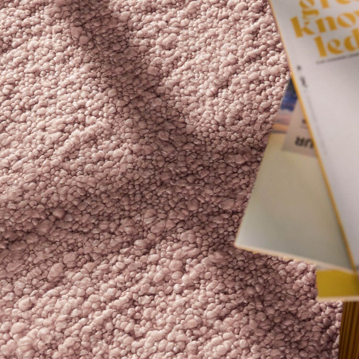 Close-up of a textured pink fabric with a product partially visible.