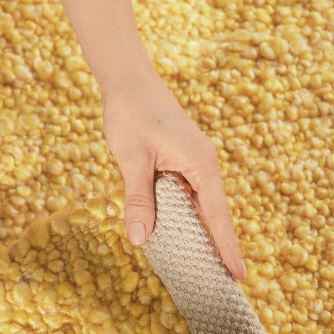Hand holding a textured object over a field of yellow corn kernels