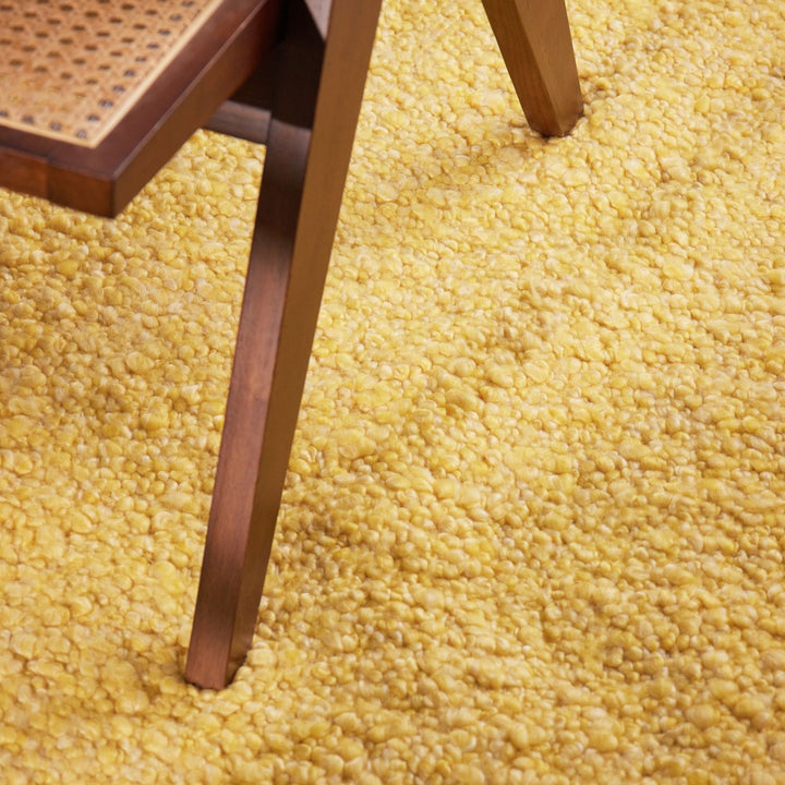 Close-up of a wooden chair leg on a textured yellow rug