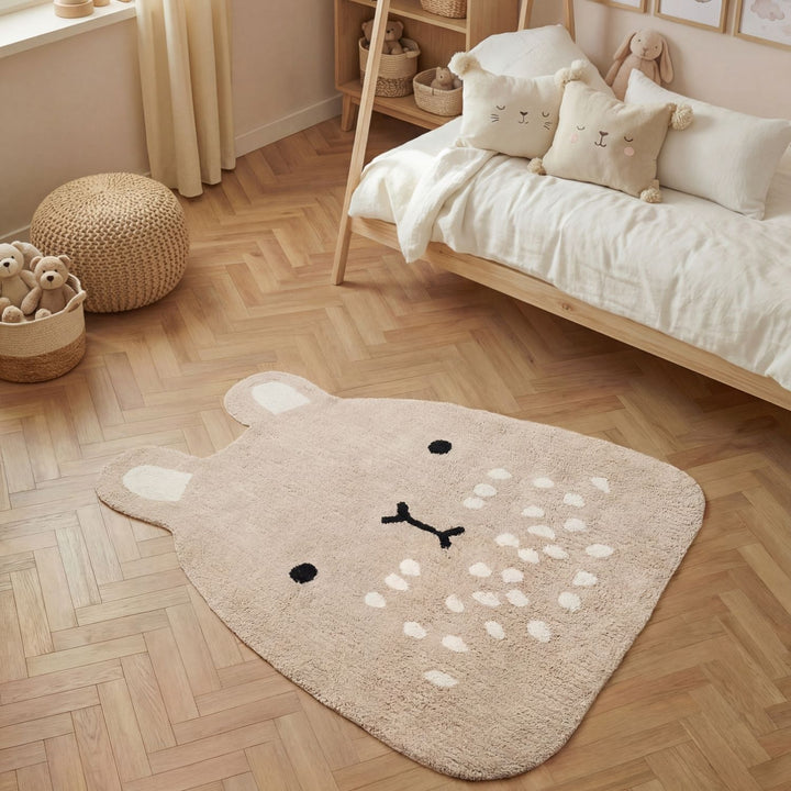 Children's room with a bear-shaped rug on a wooden floor, bed with pillows, and toys.