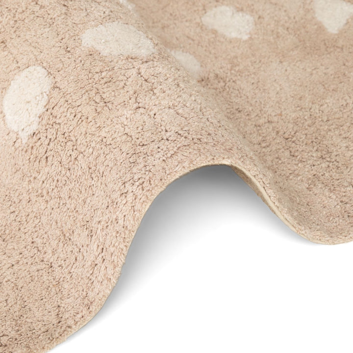 Close-up of a beige bath mat with white circular patterns on a white background