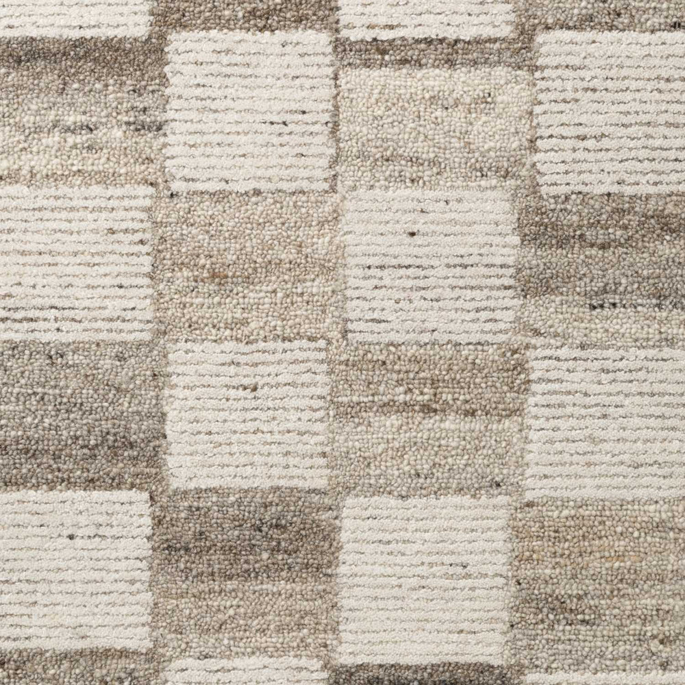Close-up of a textured carpet with a checkered pattern in beige and brown tones.