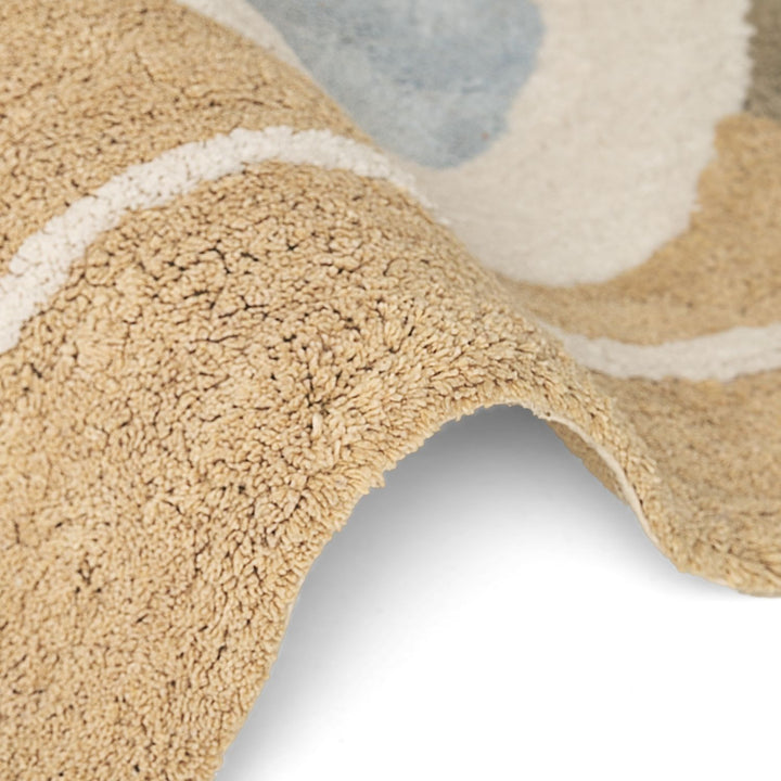 Close-up of a textured beige rug with abstract patterns on a white background