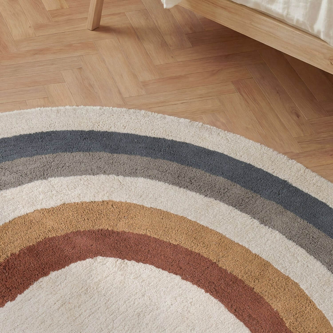 Round rug with multicolored stripes on a wooden floor