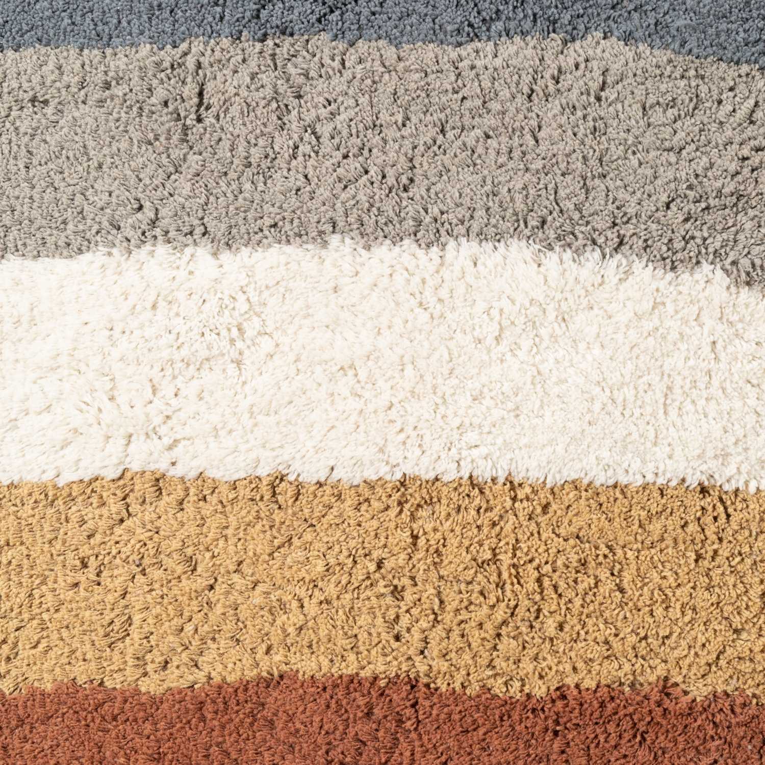 Close-up of a textured rug with horizontal stripes in gray, white, beige, and brown.