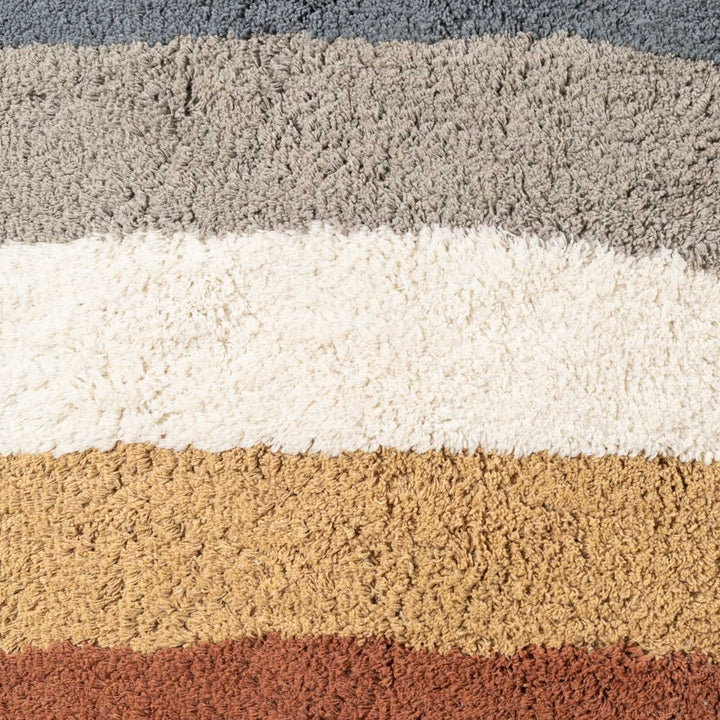 Close-up of a textured rug with horizontal stripes in gray, white, beige, and brown.