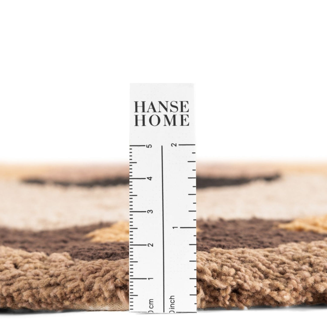 Textured carpet sample with a ruler for measurement, branded 'HANSE HOME'.