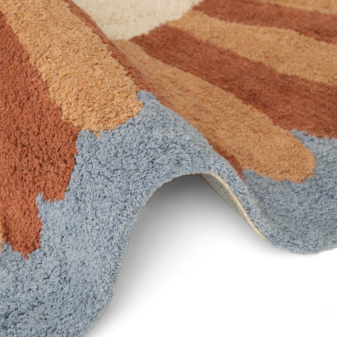 Close-up of a multicolored rug with brown, beige, and blue stripes on a white background.
