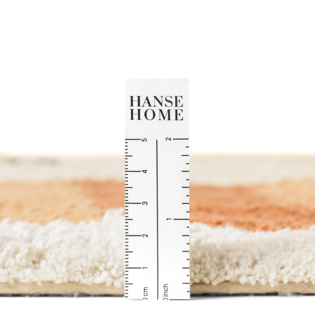 Close-up of a rug with a ruler for scale, featuring &