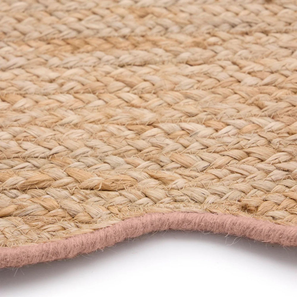 Close-up of a woven natural fiber rug with a pink border on a white background
