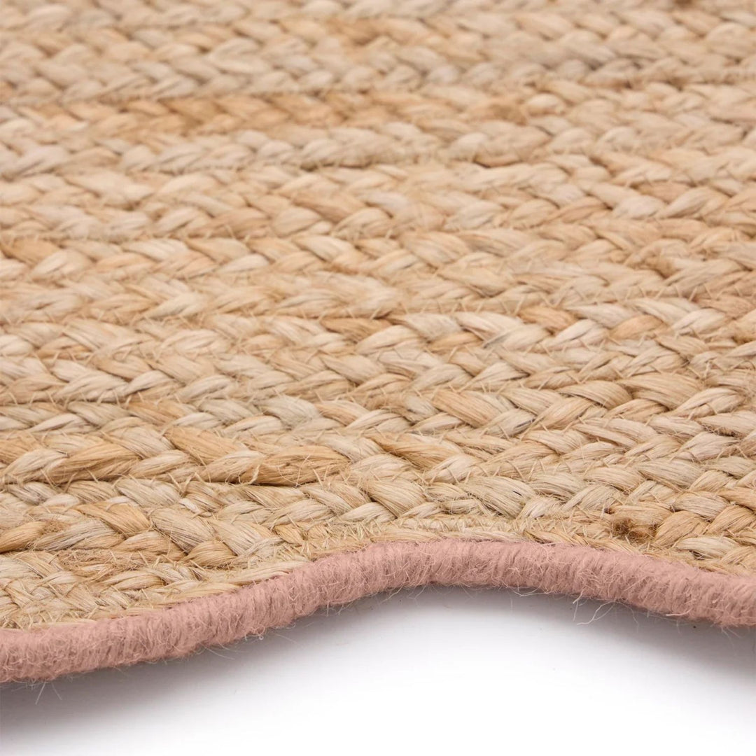 Close-up of a woven natural fiber rug with a pink border on a white background