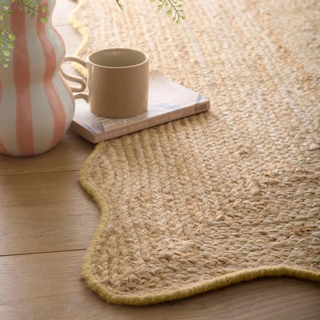 Natural woven rug on a wooden floor with a cup and vase.