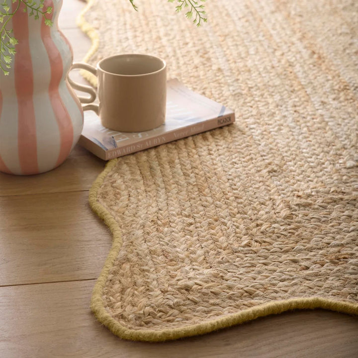Natural woven rug on a wooden floor with a cup and vase.