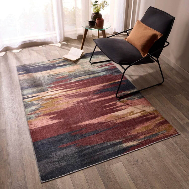 Multicolored abstract patterned rug on a wooden floor with a modern chair.