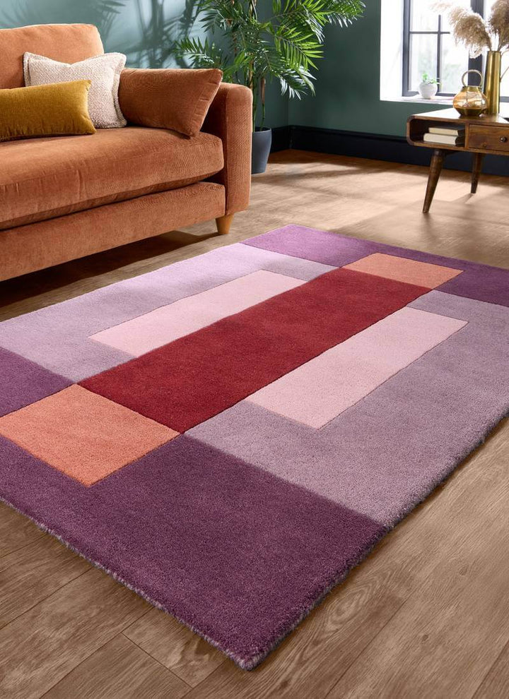 Hand-carved multicolour geometric wool rug in modern living room with orange sofa and decorative pillows.