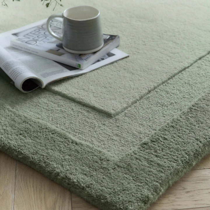 Green rug with a gray mug and newspaper on top