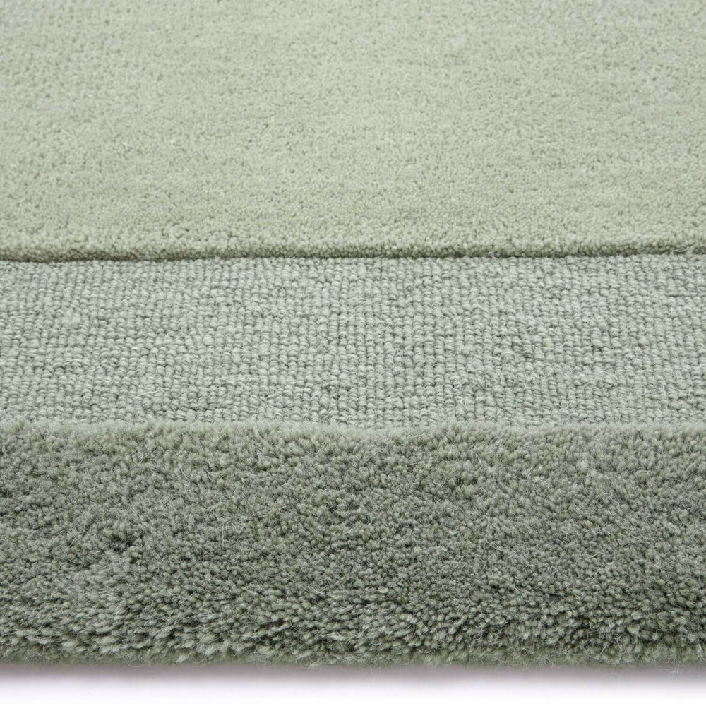 Close-up of a textured green rug with a white border