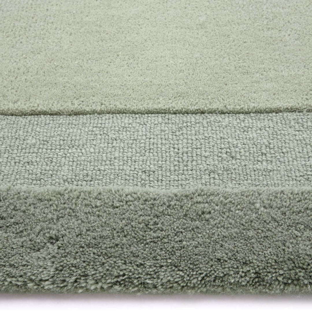 Close-up of a textured green rug with a white border