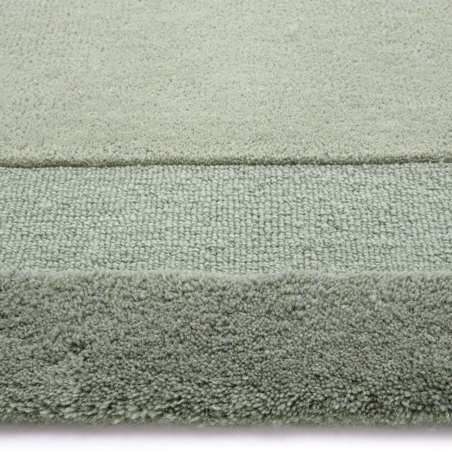 Close-up of a textured green rug with a white border