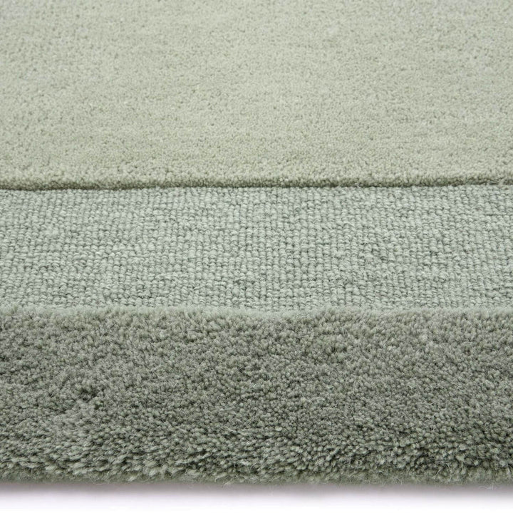 Close-up of a textured green rug with a white border