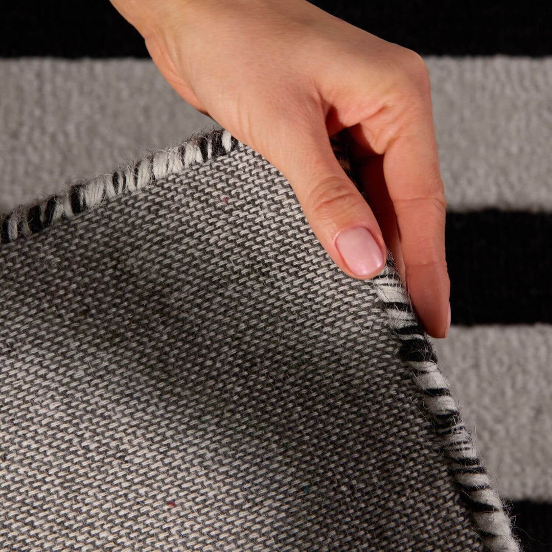 Hand touching a textured gray fabric with a black and white pattern