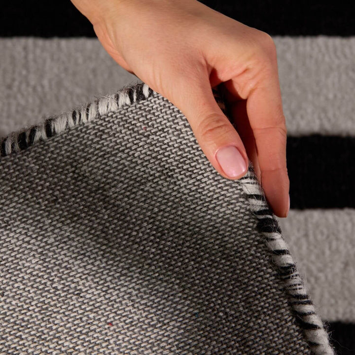 Hand touching a textured gray fabric with a black and white pattern