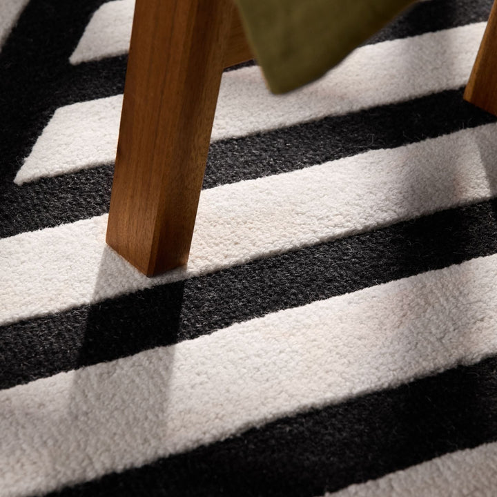 Close-up of a black and white striped rug with wooden furniture legs.