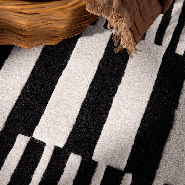 Close-up of a black and white striped rug with a woven basket on top.