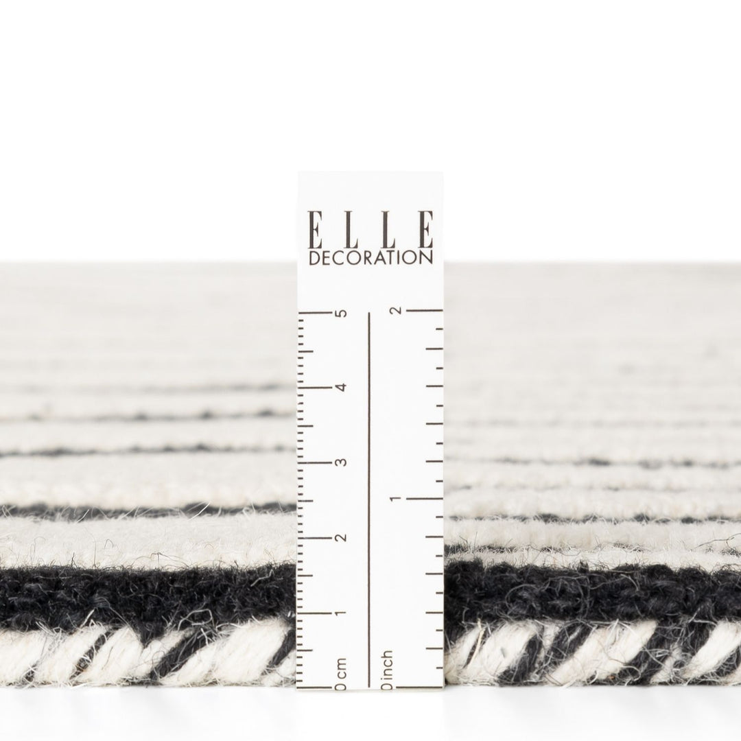Textured black and white fabric swatch with a ruler for scale, branded 'ELLE Decoration'.