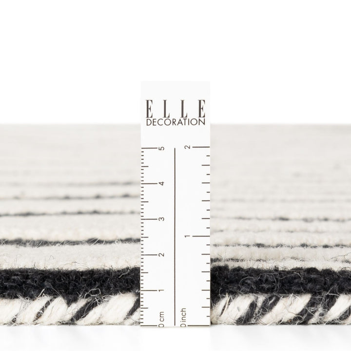 Textured black and white fabric swatch with a ruler for scale, branded 'ELLE Decoration'.