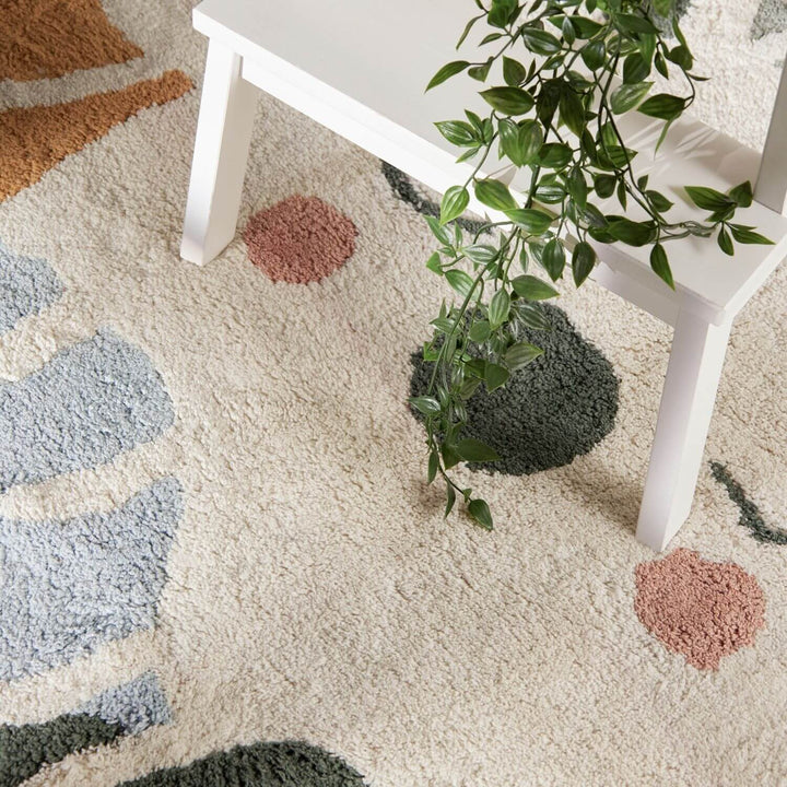 Patterned rug with geometric shapes and a white table with a plant on it