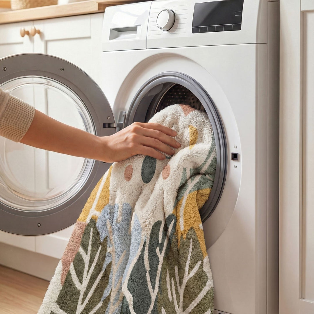 Person taking a colorful towel out of a washing machine in a kitchen.