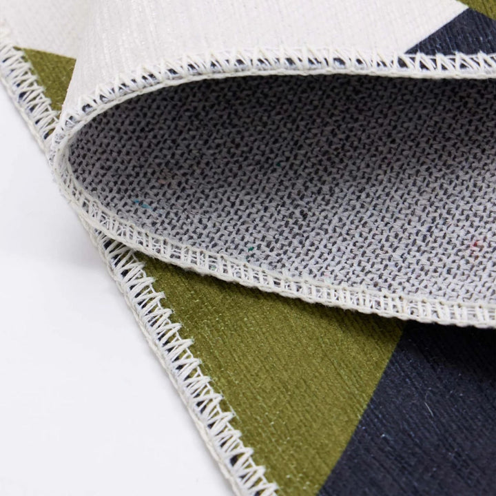 Close-up of a geometric-patterned rug with a focus on the texture and stitching.