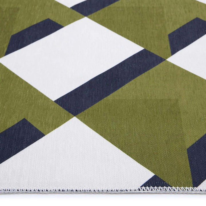 Close-up of a geometric patterned rug with green, navy, and white colors.