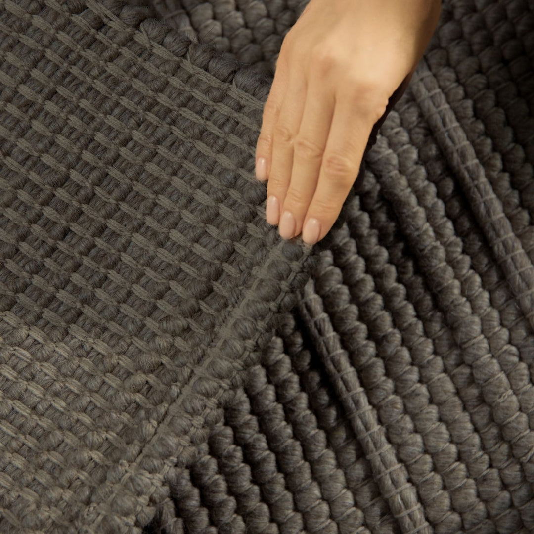 Close-up of a hand touching a textured gray fabric surface