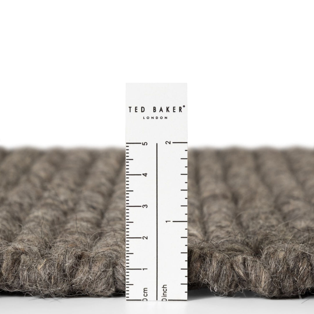 Close-up of a textured fabric with a ruler and 'Ted Baker London' label.