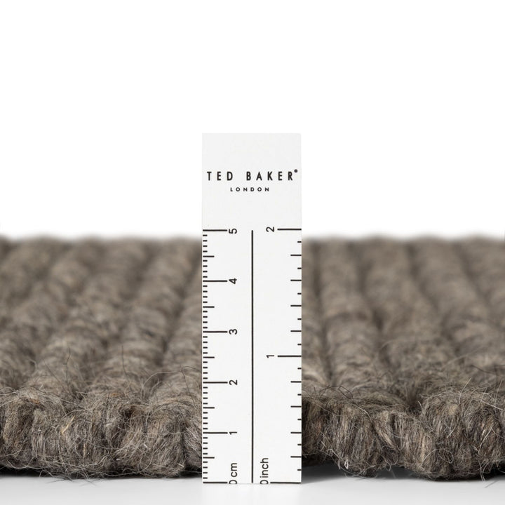 Close-up of a textured fabric with a ruler and 'Ted Baker London' label.