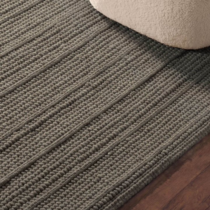 Close-up of a textured gray rug on a wooden floor.
