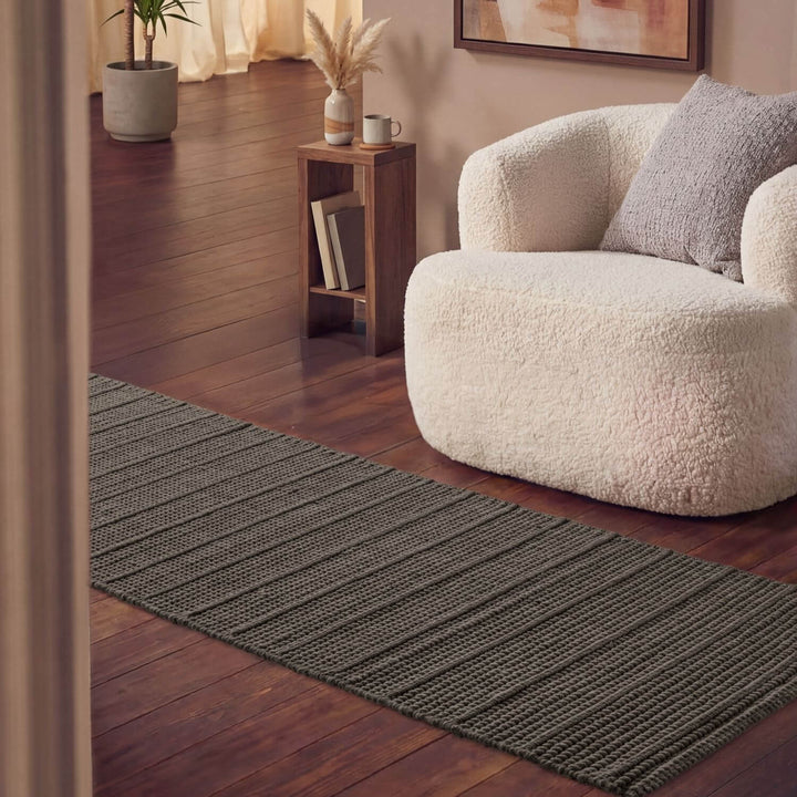 Living room with a textured gray rug, white sofa, and wooden side table.