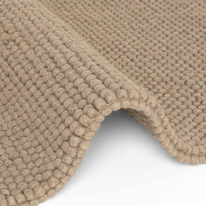 Close-up of a beige textured rug on a white background