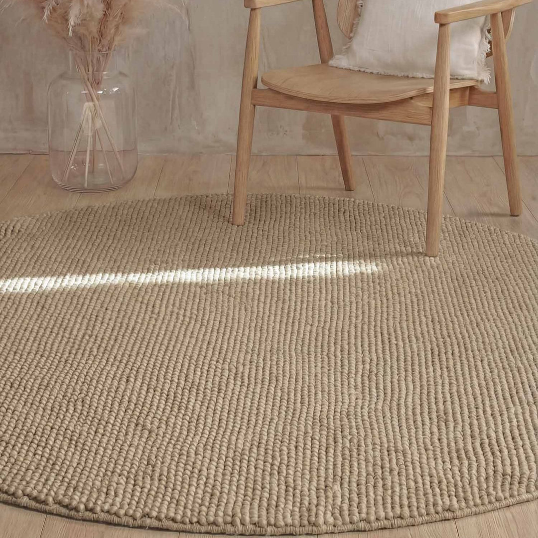 Beige textured rug with a wooden chair and vase in the background