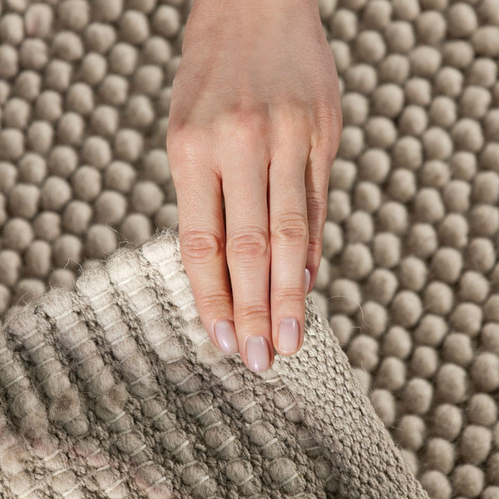 Hand touching a textured gray surface with a neutral background