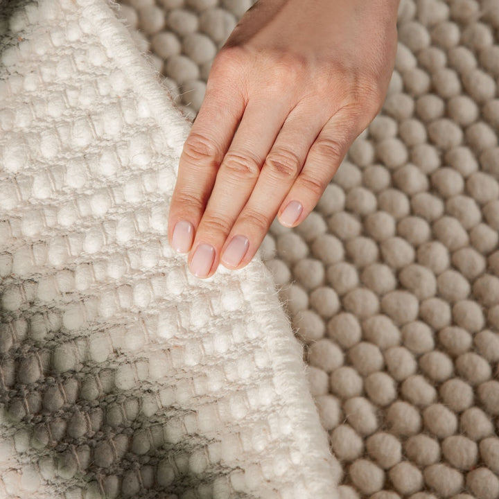Hand resting on a textured surface with a neutral color palette