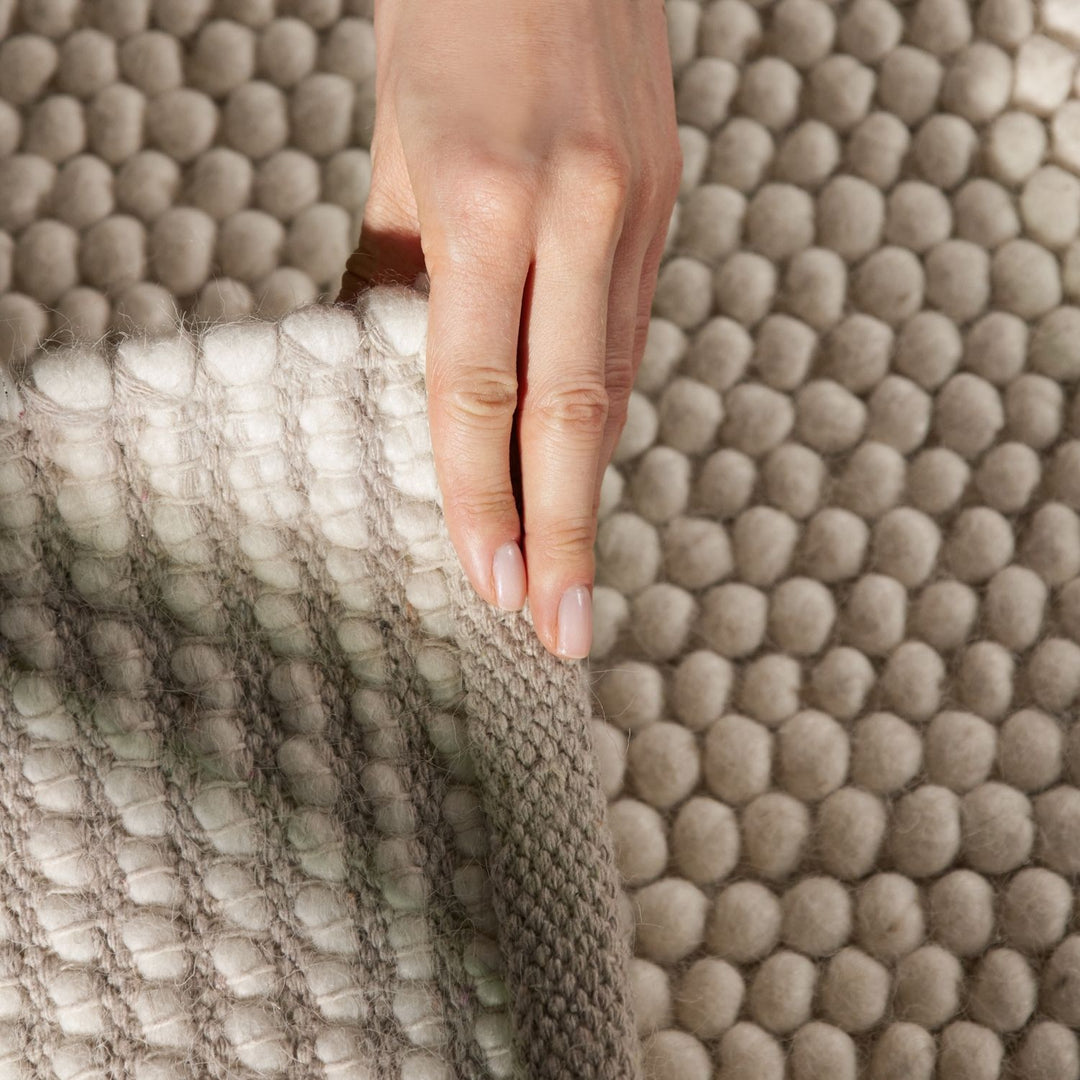 Close-up of a hand touching a textured beige fabric surface
