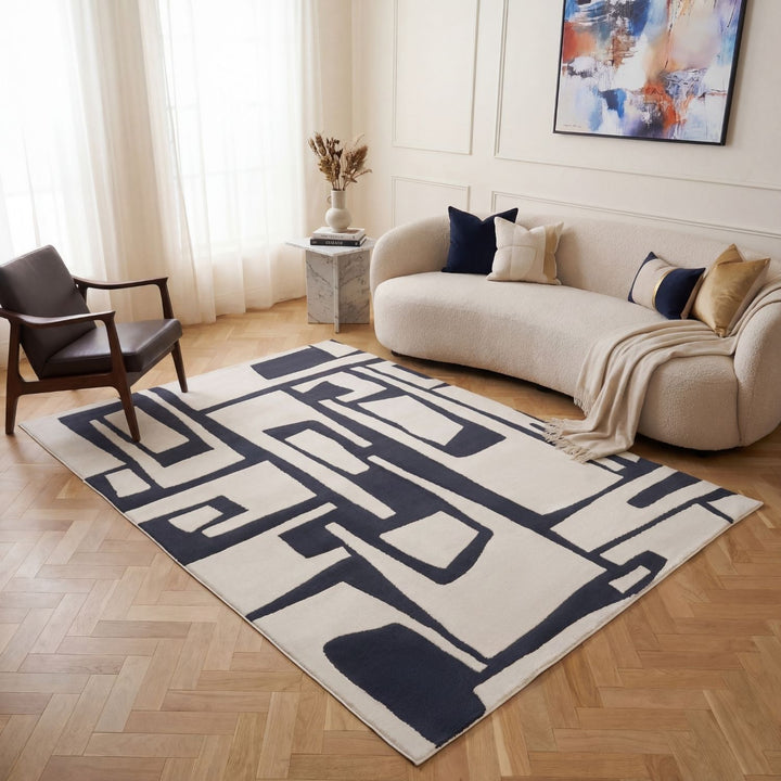 Living room with a geometric patterned rug, beige sofa, and abstract painting.